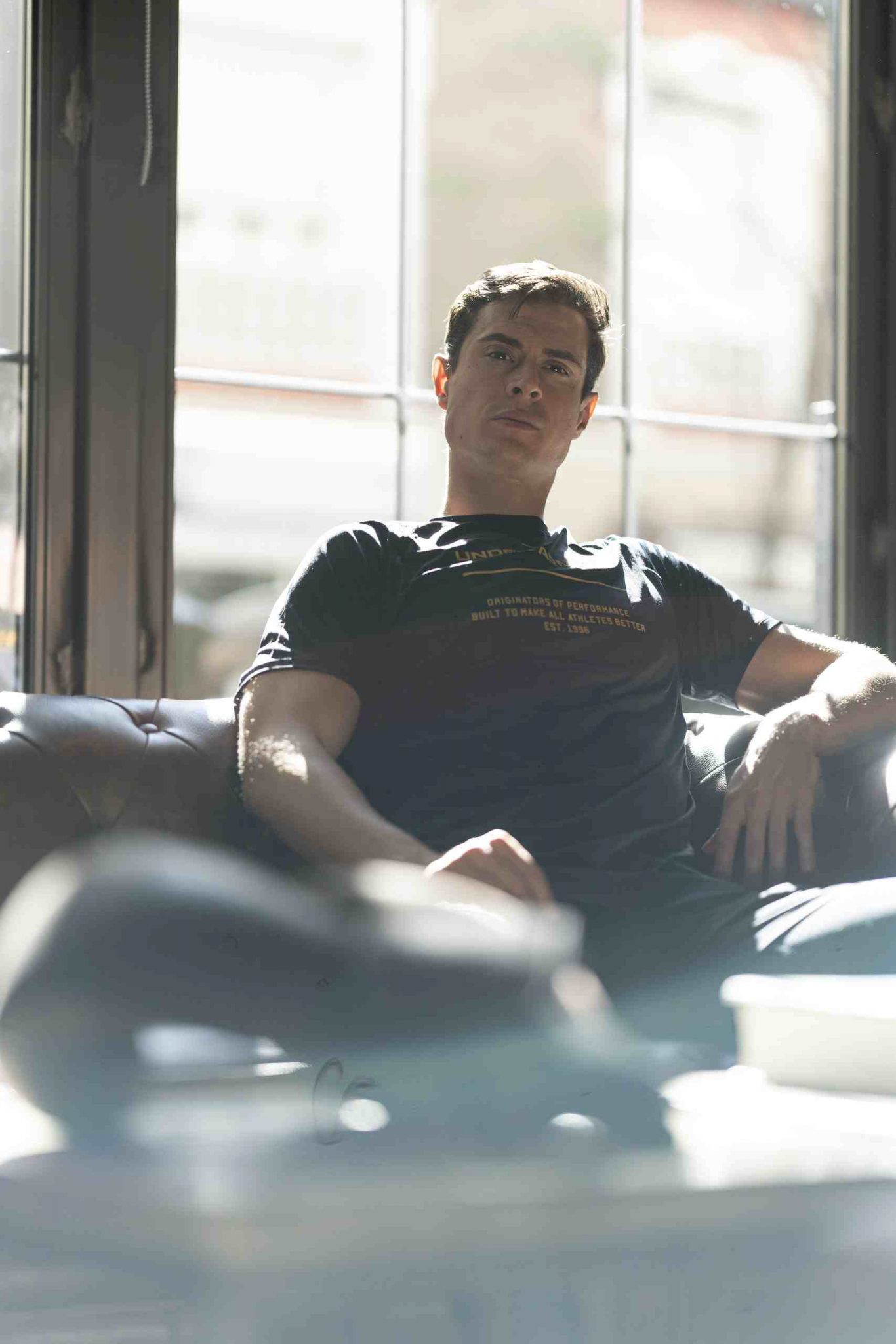 Entrenador personal en Madrid sentado en un sofá, reflejando confianza y profesionalismo en fitness personalizado. 3 mes online